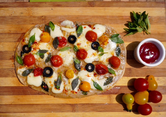 Whole wheat flat bread pizza topper with cherry tomatoes and fresh Basil leaves